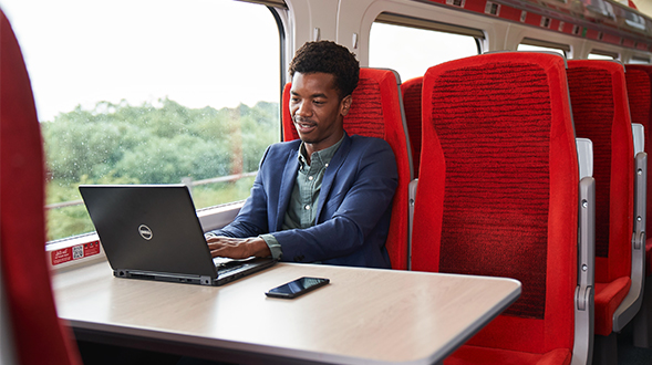 Man sat on train working on laptop